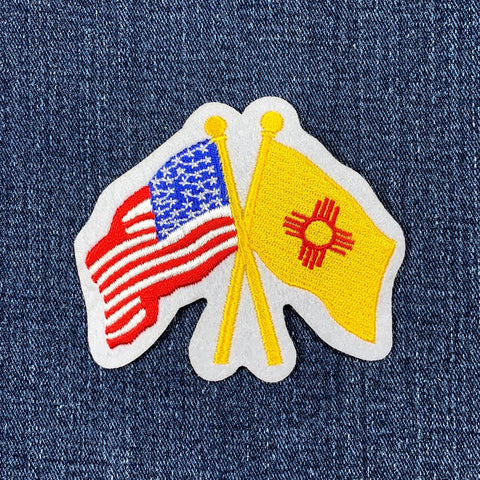 A patch featuring crossed American and New Mexico state flags on a denim background.