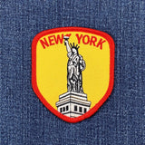 a red and yellow new york statue of liberty patch displayed on a denim background