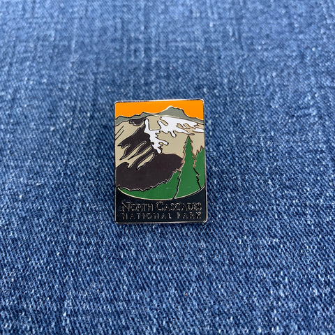 Pin with north cascades national park mountain design on a blue denim background