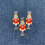 Three embroidered nutcracker soldier patches on denim fabric