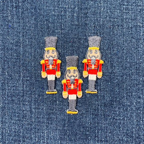 Three embroidered nutcracker soldier patches on denim fabric