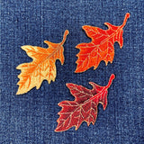 Three embroidered oak leaf patches on denim fabric