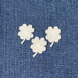 Three white clover patches on a blue denim background