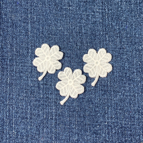 Three white clover patches on a blue denim background