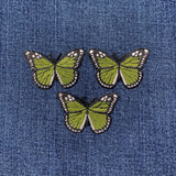 Three green butterfly patches on a denim background