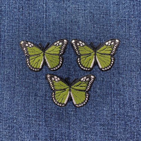 Three green butterfly patches on a denim background