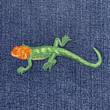 Embroidered lizard design on denim fabric