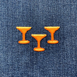 Three orange cocktail glass-shaped patches on blue denim fabric