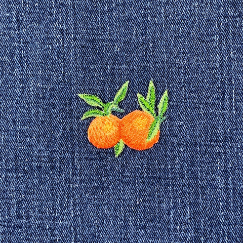 Embroidered patch of oranges on a denim fabric background