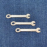 Three metallic wrench patches on a blue denim background