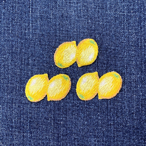 Yellow lemon embroidered patches on a denim background