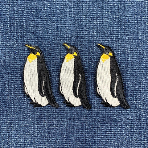 Three penguin patches on a denim background