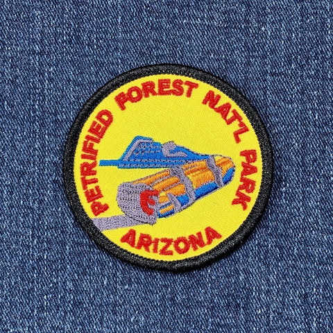 A round embroidered patch featuring the Petrified Forest National Park emblem with yellow background and text 'Arizona' on a denim background