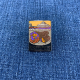A collectible pin featuring an artistic representation of Petrified Forest National Park on a denim background