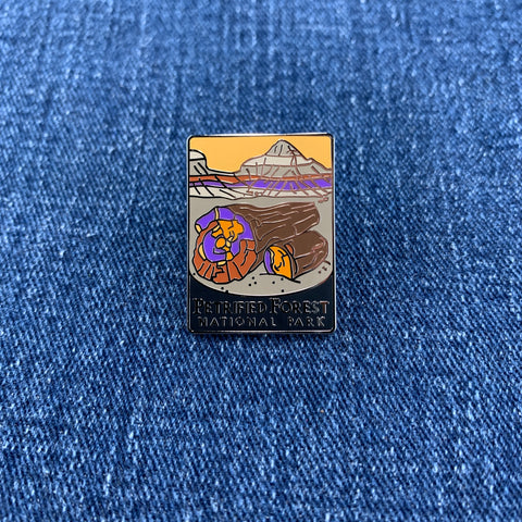 A collectible pin featuring an artistic representation of Petrified Forest National Park on a denim background
