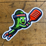 A vinyl decal of a cartoon pickle character playing pickleball with a paddle.