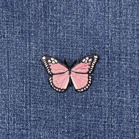 Pink butterfly patch on blue denim fabric
