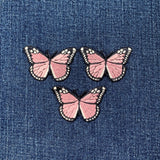 Three pink butterfly patches on a denim background