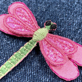 Pink and green embroidered dragonfly patch on denim fabric
