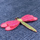 Pink and green dragonfly patch on denim fabric