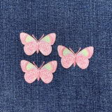 Three pink butterfly patches on a denim background
