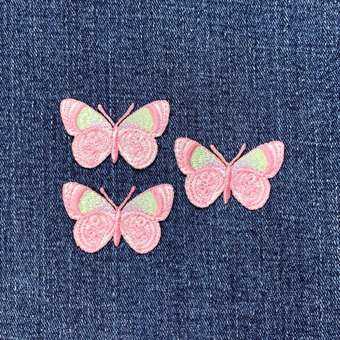 Three pink butterfly patches on a denim background