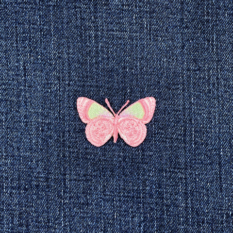 Pink butterfly patch on blue denim fabric
