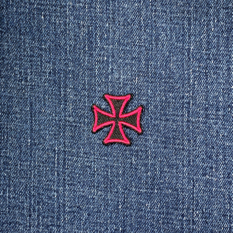 Pink and black cross patch on blue denim fabric