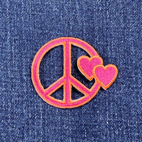 Pink peace symbol with hearts on denim fabric