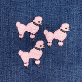 Three pink poodle-shaped patches on a denim background