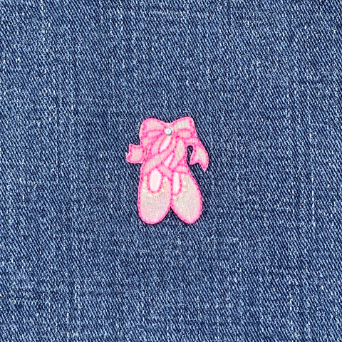 Pink embroidered ballet slipper patch on denim fabric