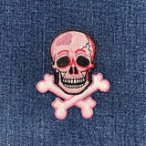 Pink skull and crossbones patch on denim fabric
