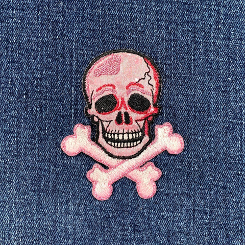 Pink skull and crossbones patch on denim fabric
