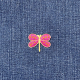 Pink and yellow dragonfly patch on blue denim fabric