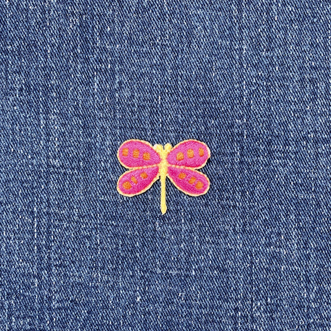 Pink and yellow dragonfly patch on blue denim fabric