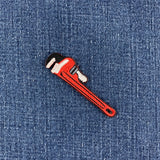 Red pipe wrench patch on denim fabric, designed for use with a plumber's uniform