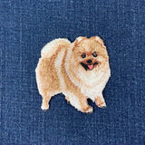 Embroidered patch of a Pomeranian dog on blue denim fabric
