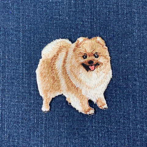 Embroidered patch of a Pomeranian dog on blue denim fabric
