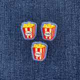 Three popcorn-themed patches on a denim background