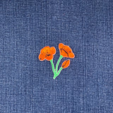 Embroidered orange flower patch on denim fabric