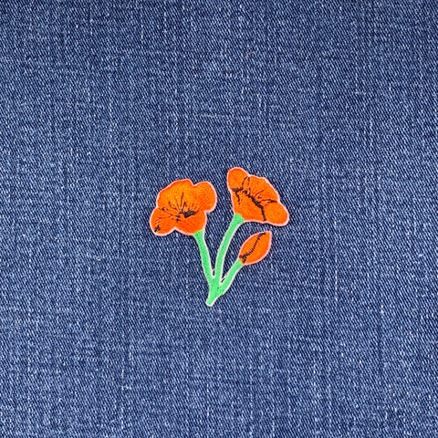 Embroidered orange flower patch on denim fabric
