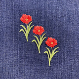 Embroidered poppy flower patches on blue denim fabric