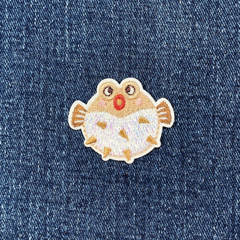 Embroidered patch of a pufferfish on denim fabric