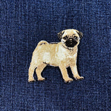 Embroidered pug dog patch on a blue denim fabric background