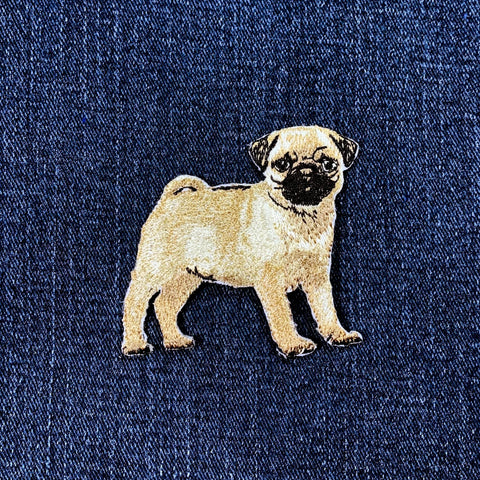 Embroidered pug dog patch on a blue denim fabric background