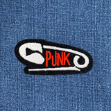 a punk safety pin patch displayed on a denim background