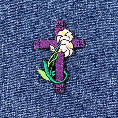 Purple cross patch with flowers on a denim background