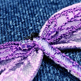 Close-up of a purple embroidered dragonfly patch on blue fabric