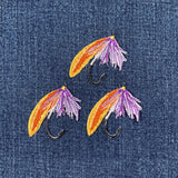 Embroidered fishing lure patches with orange and purple details on denim fabric