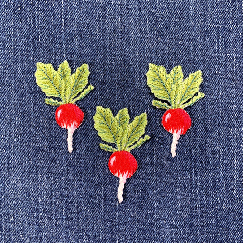 Three embroidered radish patches on denim fabric